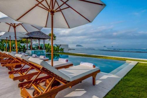 un groupe de chaises et de parasols à côté d'une piscine dans l'établissement Villa Oceana, Candidasa, à Candidasa