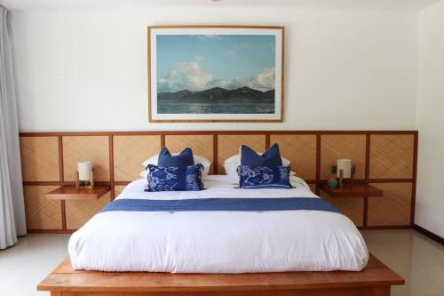 a bedroom with a large bed with blue pillows at Villa Oceana, Candidasa in Candidasa