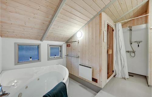 エーベルトフトにあるLovely Home In Ebeltoft With Wifiの木製の天井のバスルーム(白いバスタブ付)