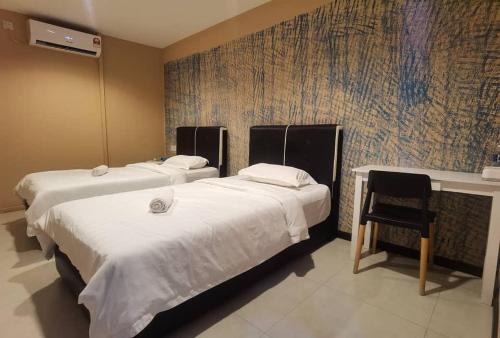 a bedroom with two beds and a chair in it at OYO HOME 90667 Chen Room Bs in Semporna