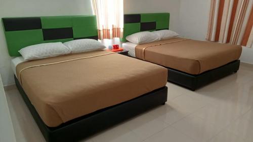 2 Betten in einem Zimmer mit Grün und Braun in der Unterkunft DLAYARAN VILLA GUEST HOUSE in Kuala Rompin