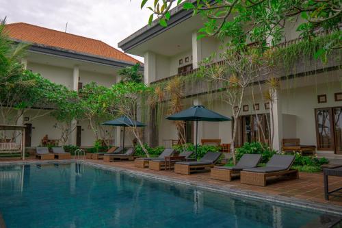 a resort with a swimming pool with chairs and umbrellas at Artini Bisma Ubud Hotel in Ubud