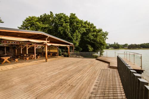 a wooden dock with a pavilion next to a lake at Hotel Glamour in Kaluža