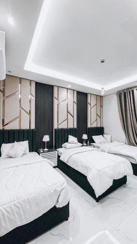 1 Schlafzimmer mit 3 Betten und weißer Bettwäsche in der Unterkunft سيلينا هاوس in Dschidda