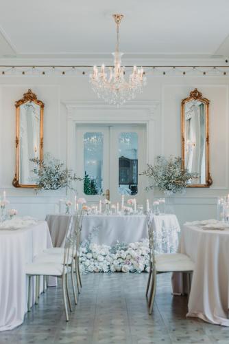 a white room with tables and chairs and a chandelier at Dwór Prezydencki Boutique Hotel & SPA in Tarnów