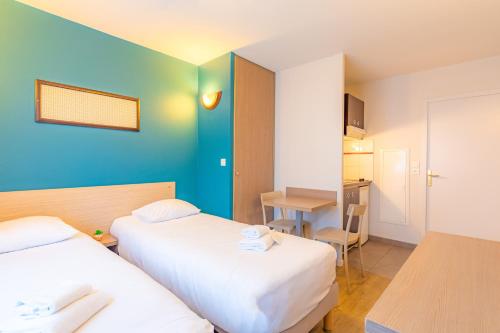 a hotel room with two beds and a table at Appart'City Classic La Roche sur Yon Centre in La Roche-sur-Yon
