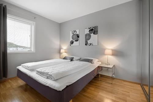 a white bedroom with two beds and a window at Frogner House - Forus Leilighetshotell in Stavanger
