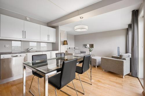 een keuken en een woonkamer met een glazen tafel en stoelen bij Frogner House - Forus Leilighetshotell in Stavanger