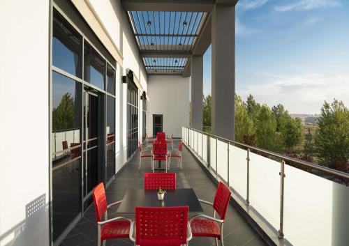 a balcony with red chairs and tables on a building at ibis Ankara Airport Hotel in Ankara