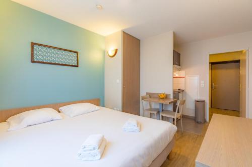 a bedroom with a white bed and a table at Appart'City Classic La Roche sur Yon Centre in La Roche-sur-Yon