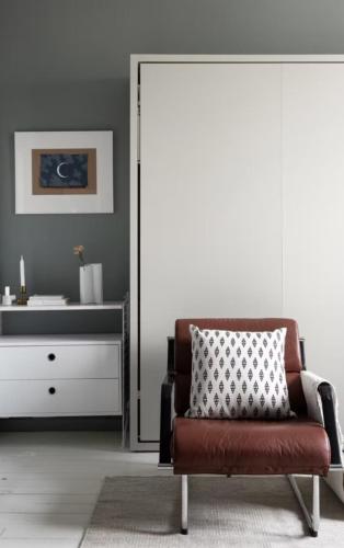ein Wohnzimmer mit einem Stuhl und einer Kommode in der Unterkunft Beautiful studio apartment in the heart of trendy Kallio in Helsinki