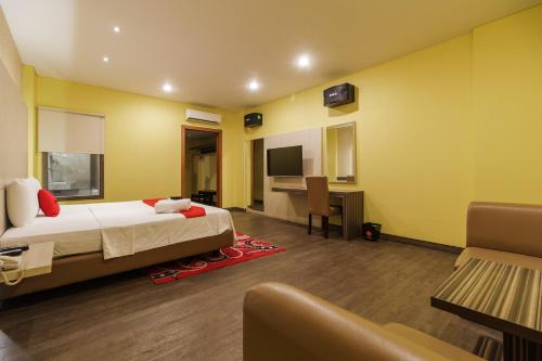 Schlafzimmer mit einem Bett, einem Schreibtisch und einem TV in der Unterkunft RedDoorz Plus near Dunia Fantasi Ancol in Jakarta