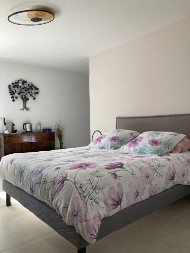 - une chambre avec un grand lit et une couverture de fleurs roses dans l'établissement Chambre d'hôtes Lavande- A l'Ombre des Tilleuls, à Lagorce