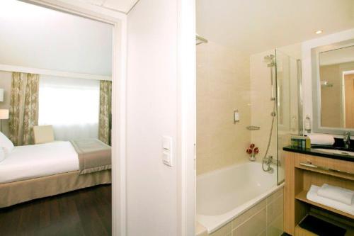 een badkamer met een bed en een bad naast een slaapkamer bij Residhome Nantes Berges De La Loire in Nantes