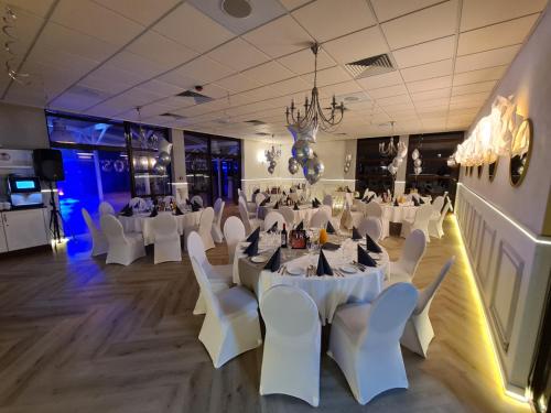 a banquet hall with white tables and white chairs at Grand Royal Hotel in Poznań