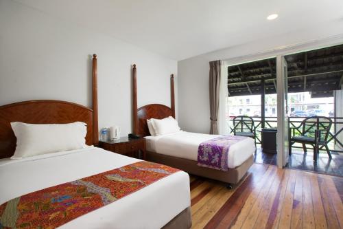a hotel room with two beds and a balcony at Adena Beach Resort in Kuantan