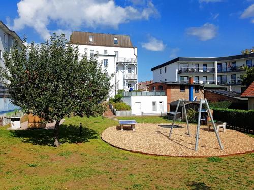 a playground in a park with a tree and a swing at Hamburg-App-07 in Ahlbeck