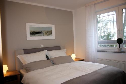 ein Schlafzimmer mit einem Bett mit zwei Lampen und einem Fenster in der Unterkunft Strandoase App. 01 in Heringsdorf