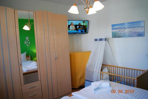 a bedroom with a crib and a tv on the wall at Bellevue-App-14 in Ahlbeck