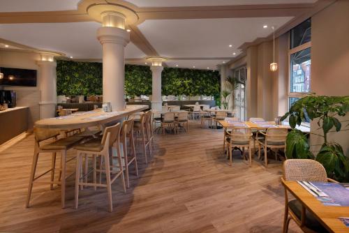 ein Restaurant mit Tischen, Stühlen und Pflanzen in der Unterkunft WestCord City Centre Hotel in Amsterdam