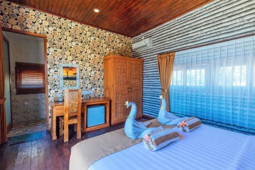 a bedroom with a bed with two swans on it at Kabeh Jati Garden Villa & Restaurant in Nusa Penida