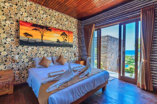 a bedroom with a bed with a view of the ocean at Kabeh Jati Garden Villa & Restaurant in Nusa Penida