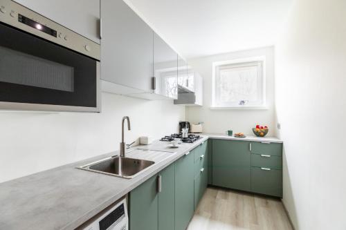 uma cozinha com armários verdes e um lavatório em P&O Apartments Gamerskiego em Varsóvia