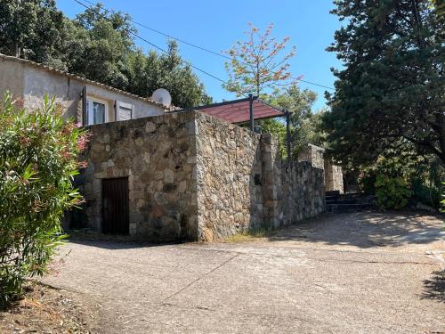 a stone house with a gate and a stone wall at Villa vue mer in Lumio