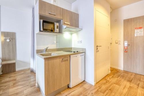 una pequeña cocina con fregadero y microondas en Aparthotel Adagio Access Saint Nazaire en Saint-Nazaire