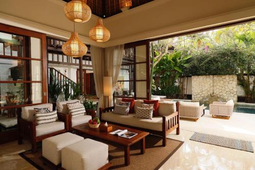 a living room with a lot of furniture and windows at Jimbaran Beach Villas by Nakula in Jimbaran