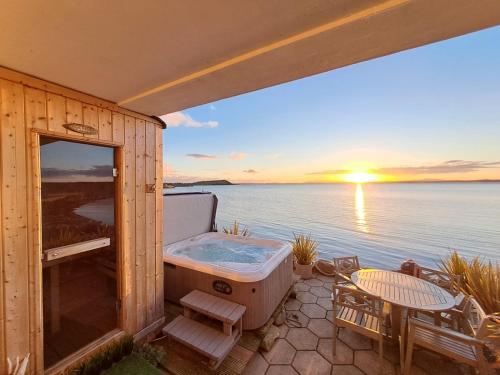 una vasca idromassaggio su un ponte con vista sull'oceano di Relaxing cottage with spectacular view, Sauna and Spa Pool a Kircubbin