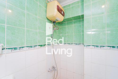 ein Bad mit grünen und weißen Fliesen und einer Dusche in der Unterkunft RedLiving Apartemen Cibubur Village - Lily's Room Tower C in Depok