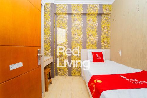 una camera da letto con un letto con un cuscino rosso sopra di RedLiving Apartemen Cibubur Village - Lily's Room Tower C a Depok