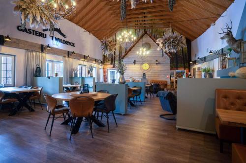 un restaurante con suelo de madera, mesas y sillas en Landgoed 't Wildryck, en Diever