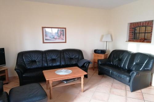a living room with black leather couches and a coffee table at Beekenhof in Bommelsen