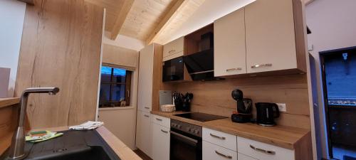 a kitchen with white cabinets and a black stove at Hochalmbahnen Chalets Rauris 1-17 WE3, Maislaufeldweg 1q OG in Rauris