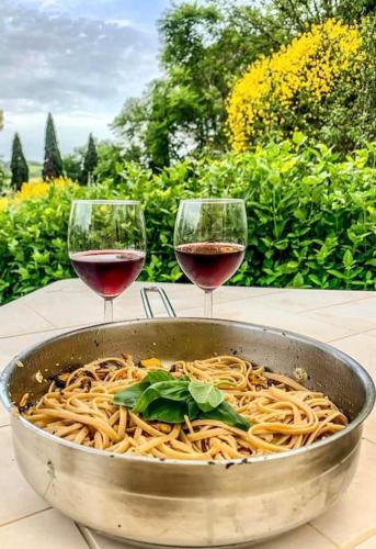 two glasses of wine next to a bowl of spaghetti at Cuore della Toscana in Radicondoli