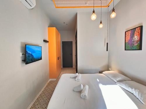 a bedroom with a large white bed and a flat screen tv at Levinski Market Hotel in Tel Aviv