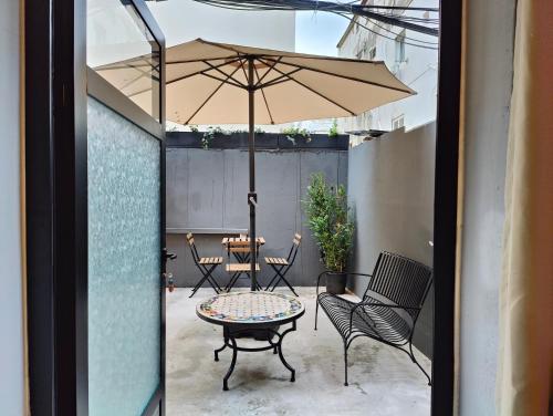 a patio with an umbrella and a table and chairs at Levinski Market Hotel in Tel Aviv
