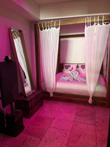 - une chambre avec un lit aux murs et rideaux roses dans l'établissement L'EXCELLENCE AVIGNON - Suite LUXE SAUNA, HAMMAM & JACCUZZI, à Avignon