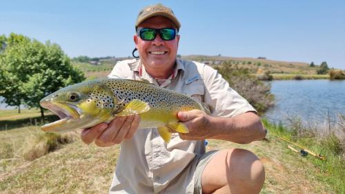 a man holding up a brown trout at Walkersons Trout and Nature Haven in Dullstroom