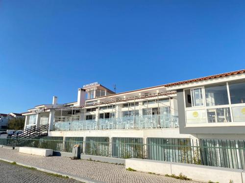 a building with a balcony with chairs on it at Hotel HS Milfontes Beach - Duna Parque Group in Vila Nova de Milfontes