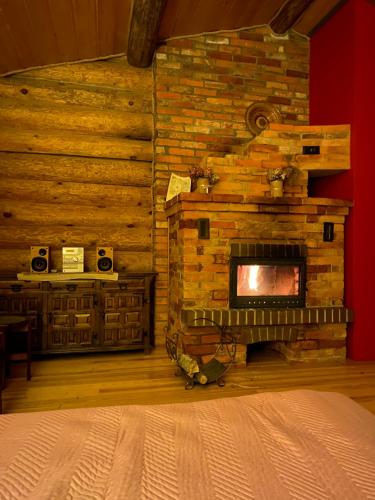 1 dormitorio con chimenea de piedra en una cabaña de madera en Dzirnavas Pirtsmāja, en Cesvaine