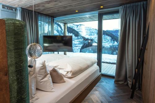 a bedroom with a bed and a large window at Luxury Chalet Vilaiet in Ortisei