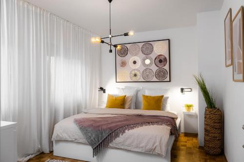 Dormitorio blanco con cama con almohadas amarillas en Apartmaji Spalina, Ivančna Gorica 