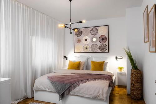 a white bedroom with a bed with yellow pillows at Apartmaji Spalina, Ivančna Gorica in Veliko Črnelo