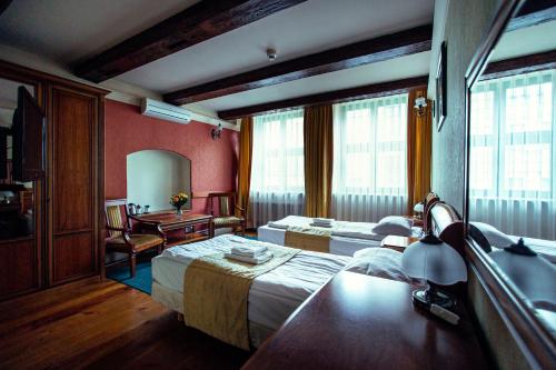 a hotel room with two beds and a desk at Heban Hotel in Toruń