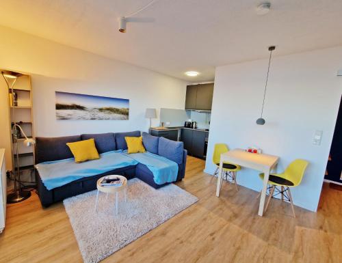 uma sala de estar com um sofá azul e uma mesa em Stadtgebiet EIC-018 em Heiligenhafen