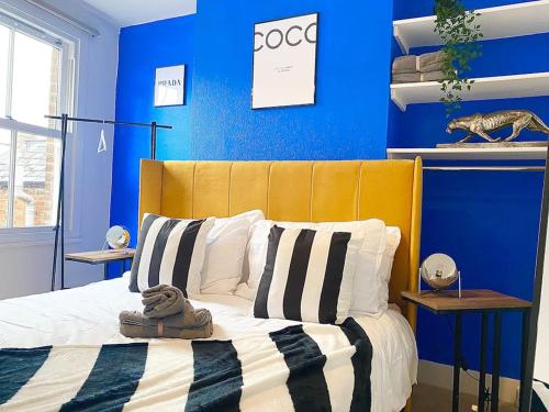 a blue bedroom with a bed with a yellow headboard at Beautiful City Centre Home With Garden and Parking in Oxford