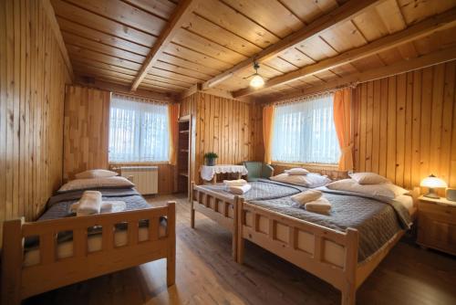 2 łóżka w pokoju z drewnianymi ścianami w obiekcie Gościniec u Marzeny w Bukowinie Tatrzańskiej
